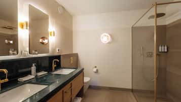 Un baño moderno con dos lavamanos, un espejo grande y cabina de ducha con paredes de vidrio.