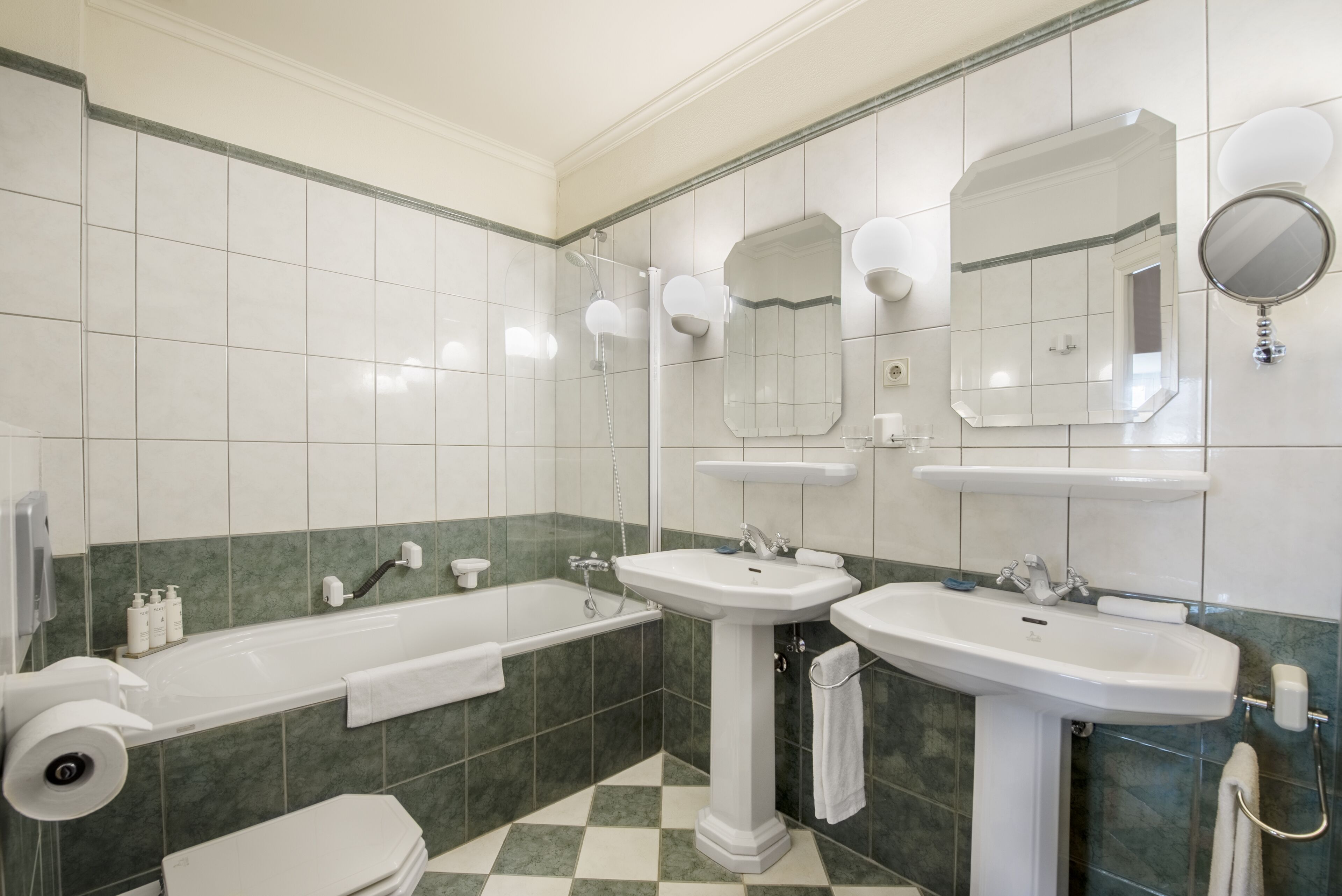 Een badkamer met een bad, twee wastafels en een toilet.