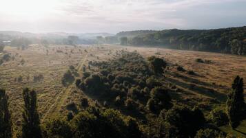 Luchtbeeld van een landelijk gebied met velden, bomen en een heldere lucht.