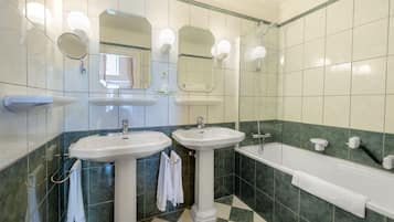 A bathroom with two sinks, a bathtub, and a shower.