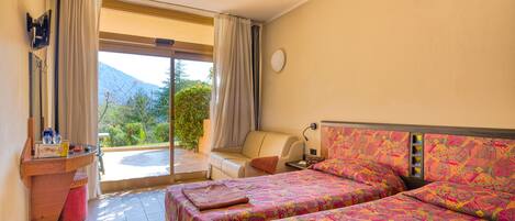 A hotel room with two beds, a small table, a chair, and a view of the outdoors.
