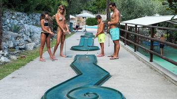 Ein Poolbereich mit einem grünen Shuffleboard-Tisch, einer Steinmauer und einem Holzzaun.