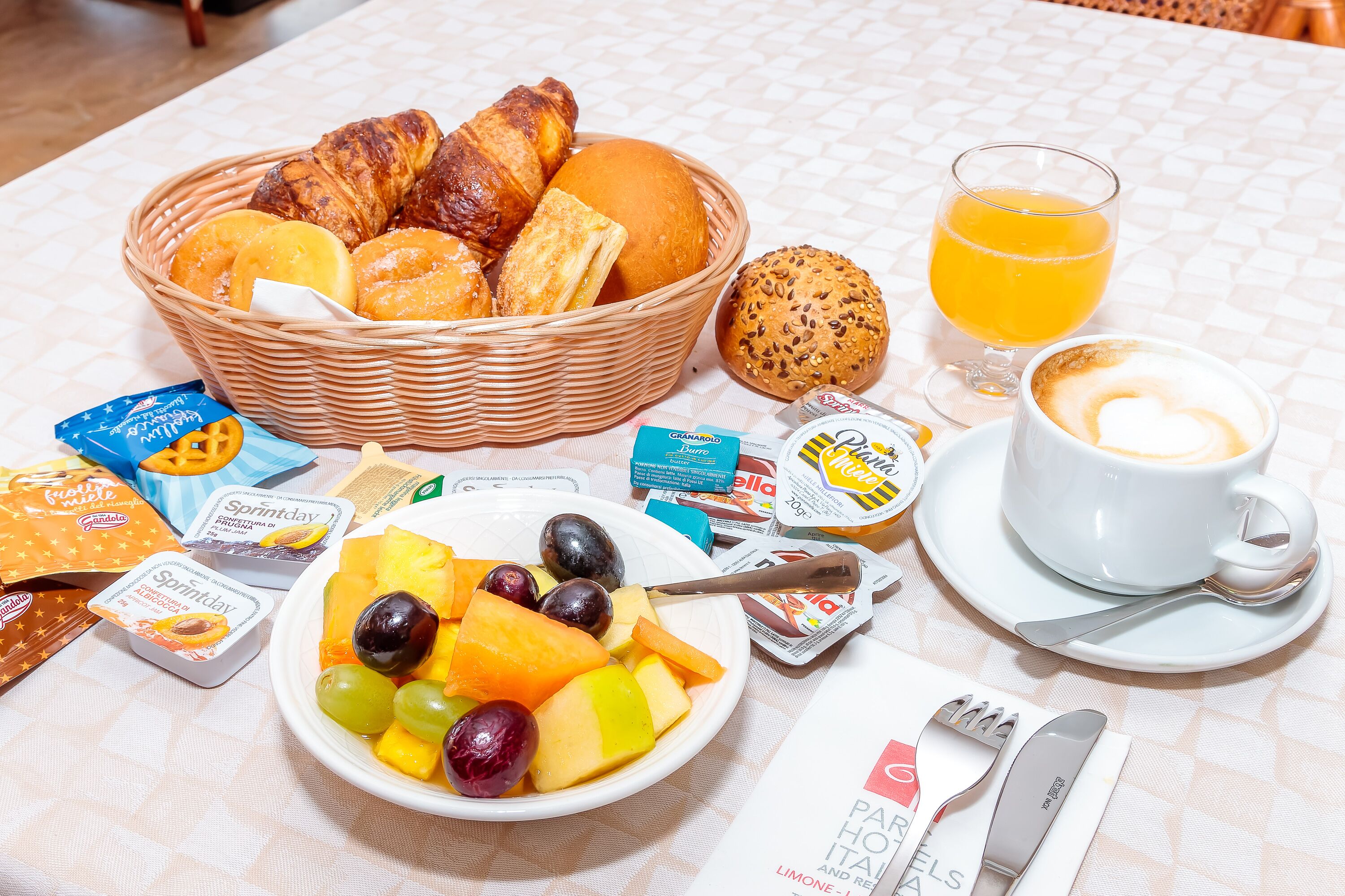 Ein Frühstückstisch mit Croissants, Orangensaft, Kaffee und einer Obstschale.