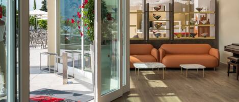 Un salon moderne doté d’une porte vitrée donnant sur un espace de détente extérieur, d’un ensemble de canapés et d’une étagère décorative pour oiseaux.