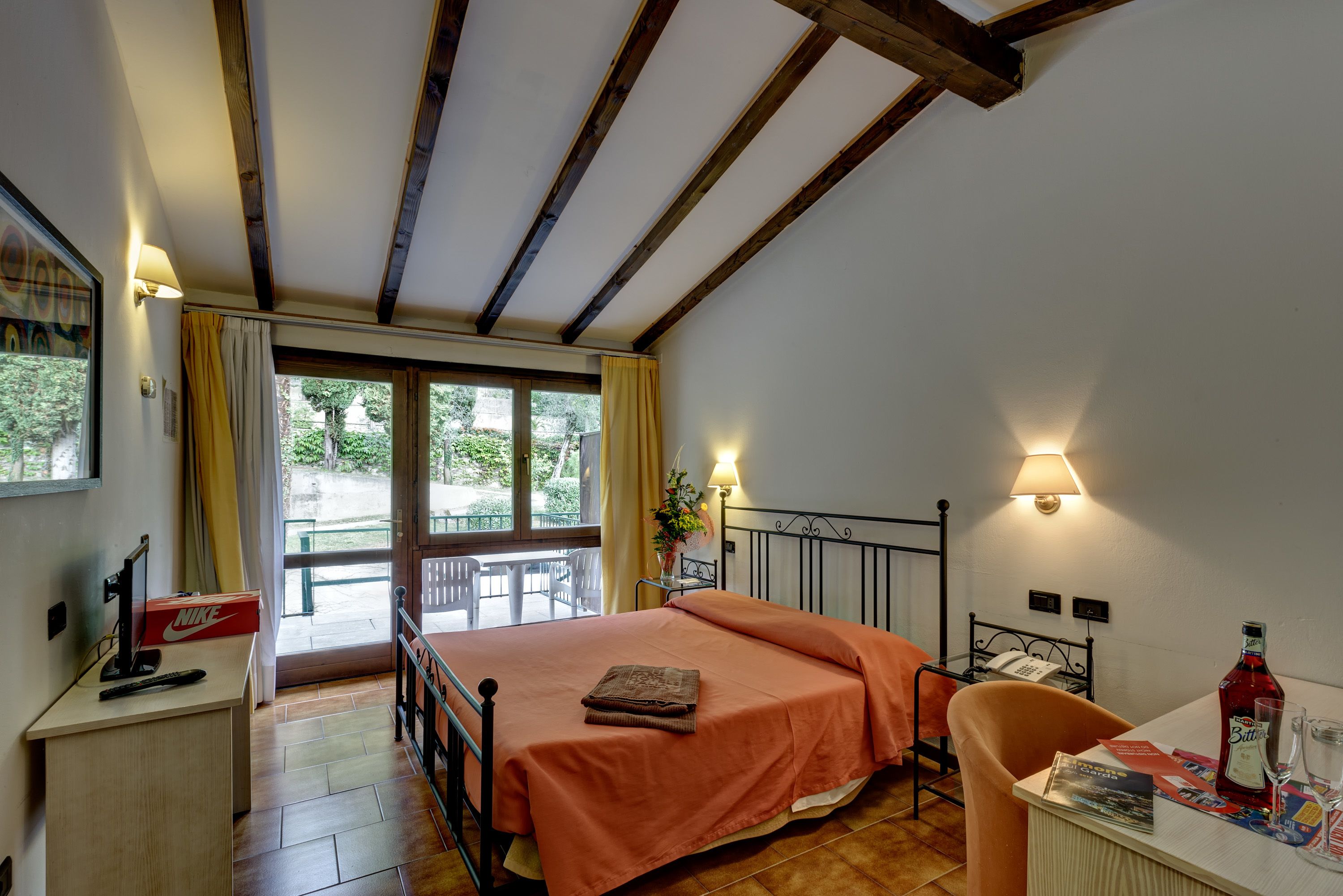 Une chambre à coucher avec un lit, un bureau, une chaise, une lampe et une fenêtre.