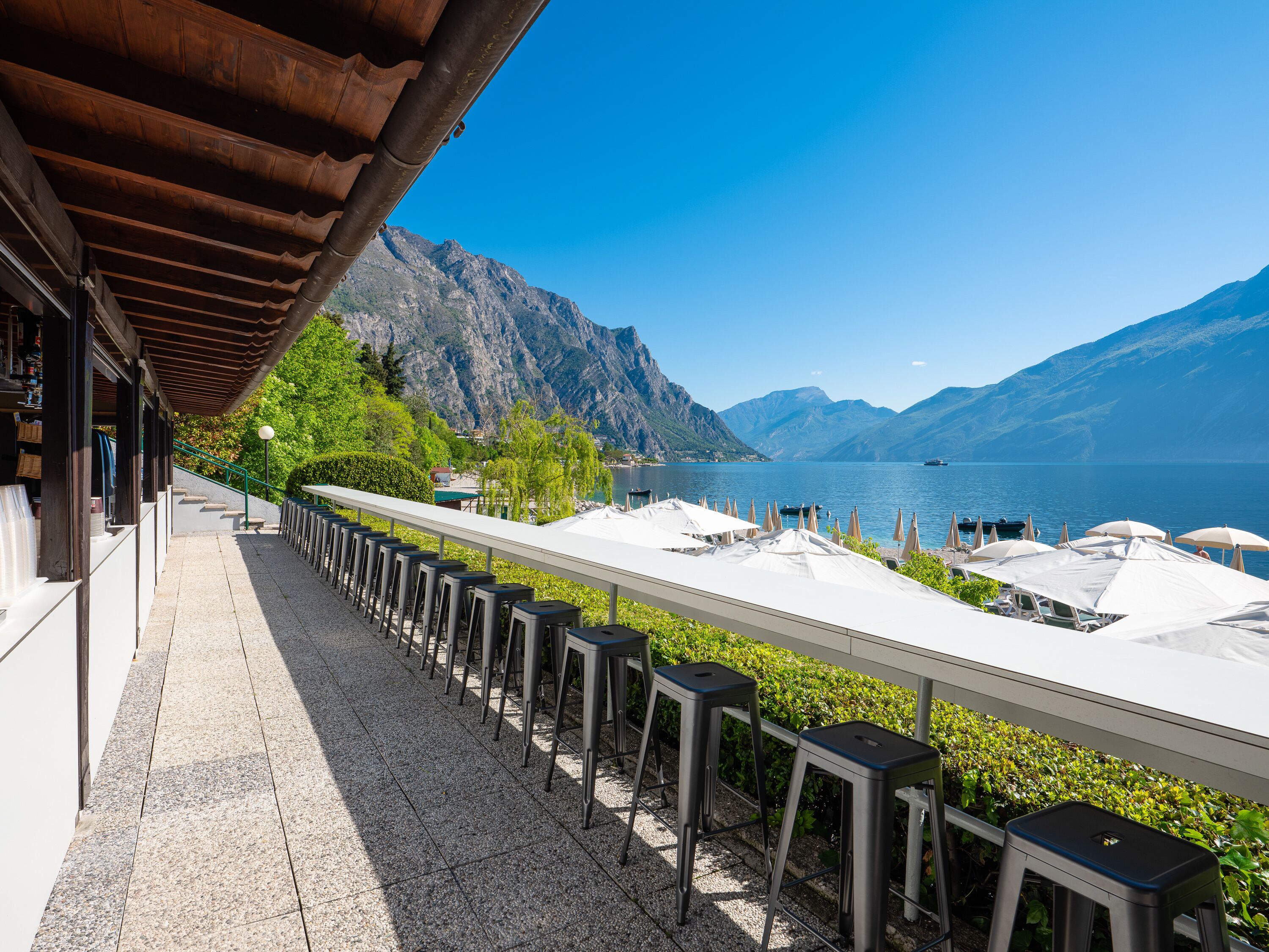 Une terrasse offrant une vue sur un lac et des montagnes, avec des sièges extérieurs et un espace abrité.