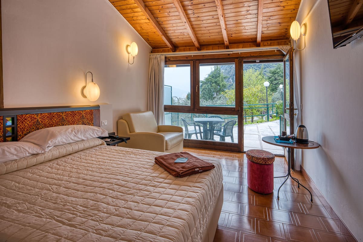 A hotel room with a large bed, a chair, a table, and a view of the outdoors.