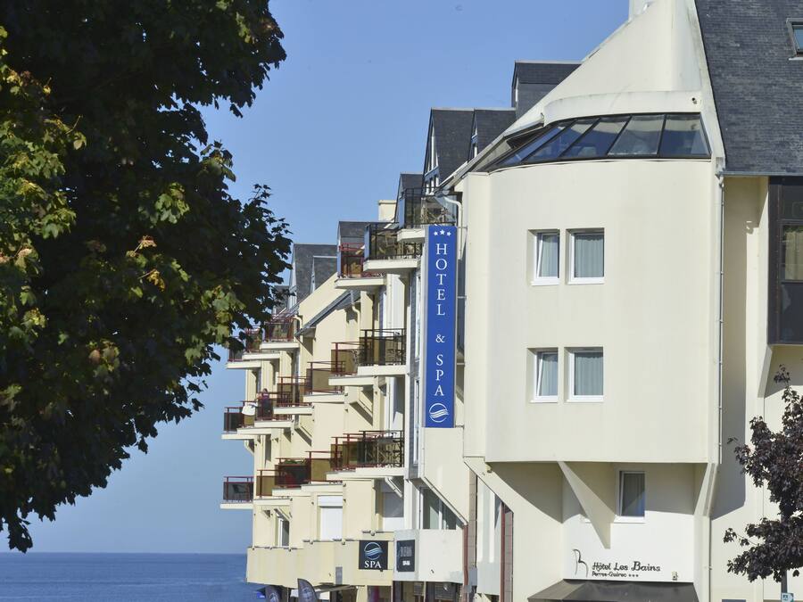 A hotel with multiple balconies, a spa sign, and a view of the sea.