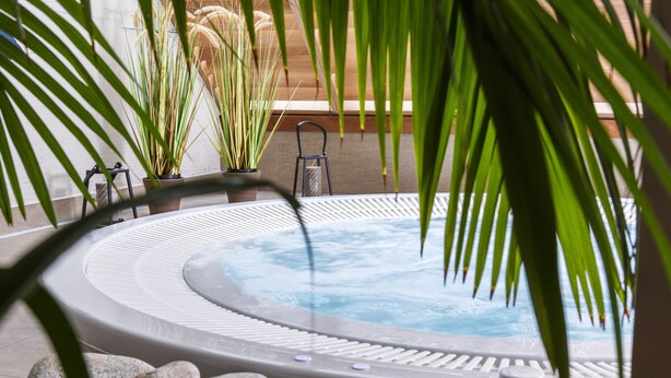 A hot tub surrounded by rocks and potted plants, with a chair and a small table nearby. - Best Western Les Bains Hôtel & SPA Perros-Guirec (Perros-Guirec)