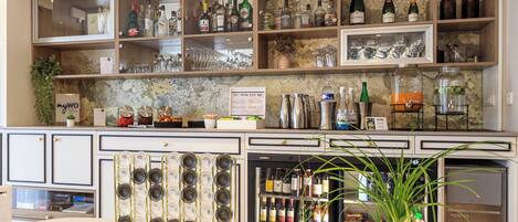 A bar area with shelves of bottles, glasses, and a wine cooler.