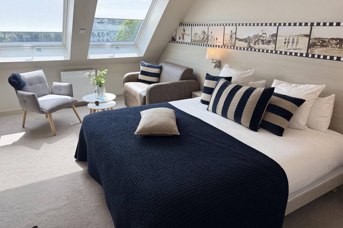 Un dormitorio con una cama grande, un sofá, una silla, una mesita y una ventana con persianas.