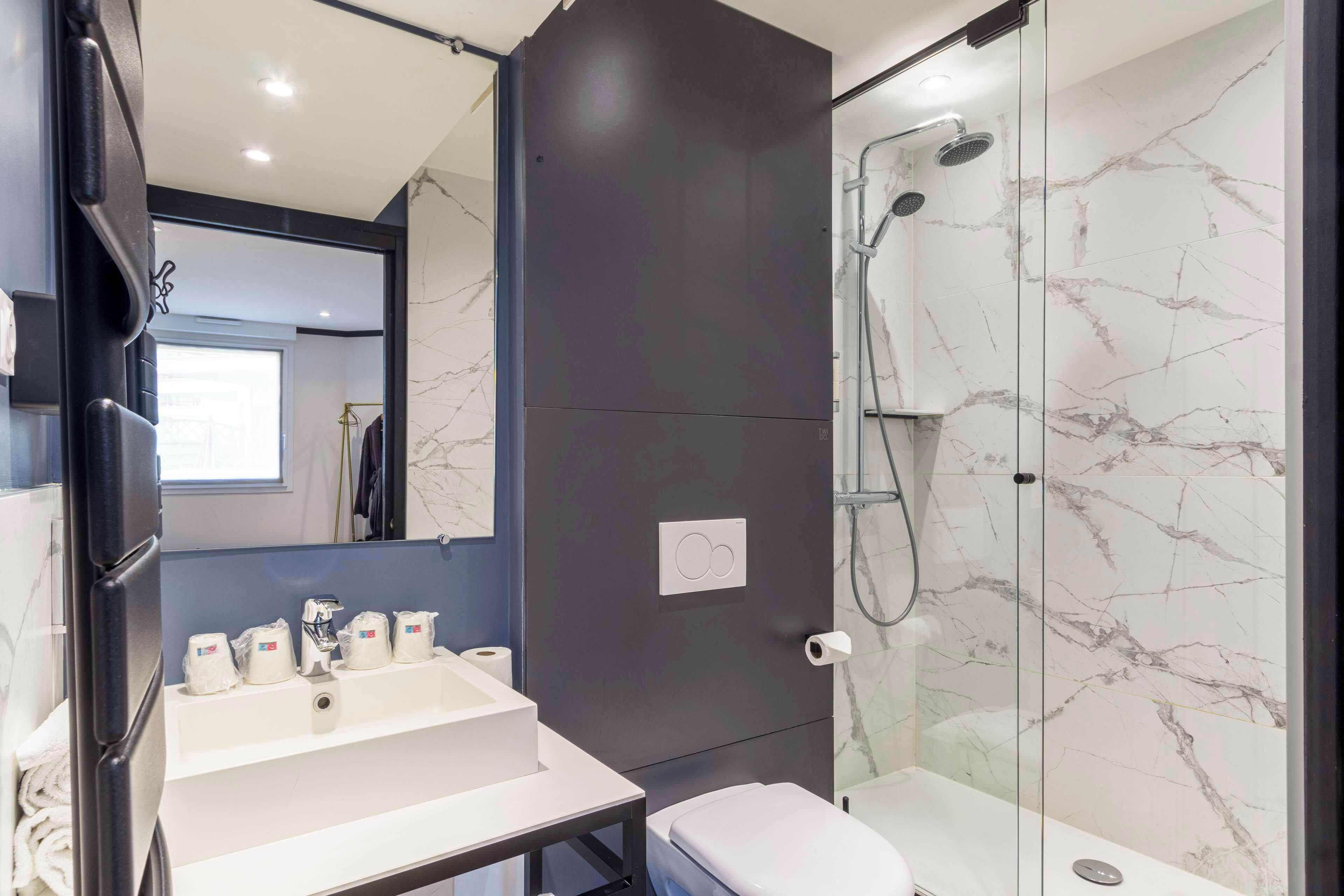 A modern bathroom with a white sink, toilet, and glass-enclosed shower.