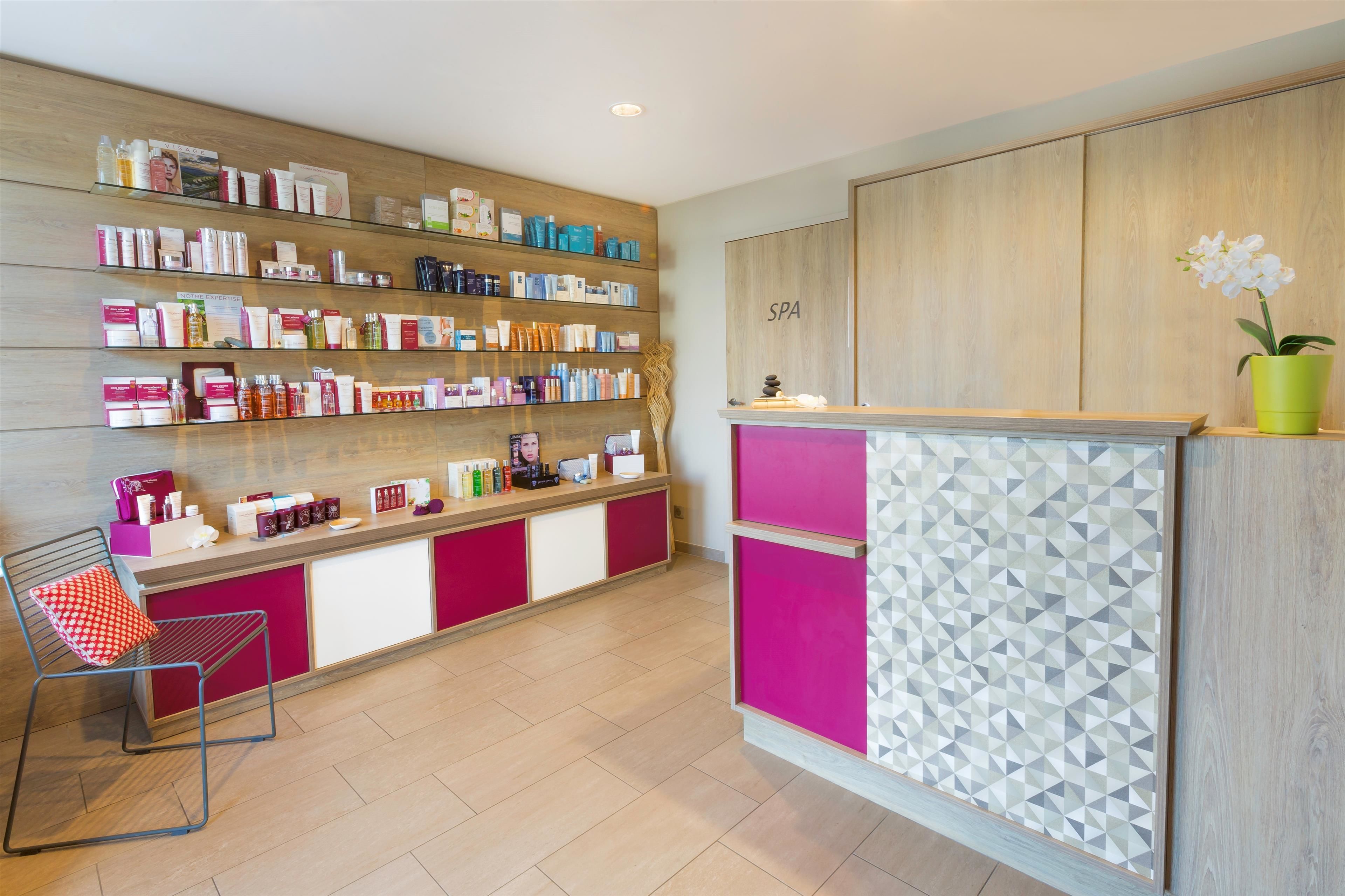 A reception area with a wooden wall, a counter with a geometric patterned panel, and a chair with a red cushion.