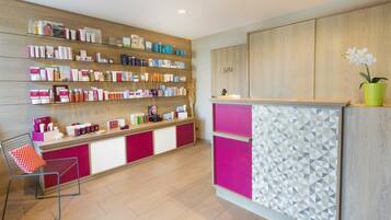 A reception area with a wooden wall, a counter with a geometric patterned panel, and a chair with a red cushion.