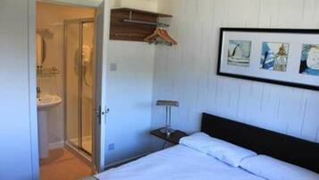 Un dormitorio con cama, mesita de noche, perchero y un cuadro enmarcado en la pared.