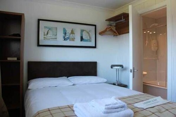 A hotel room with a bed, a framed artwork above it, a wardrobe, and a bathroom visible through an open door. - Brander Lodge Hotel (Taynuilt)