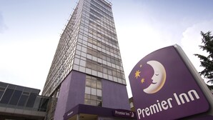Un edifici alt amb façana de vidre i un cartell de Premier Inn.