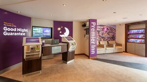 Zona de recepció d'hotel amb un taulell d'eixida, quioscos d'autoserveis, una zona de seients i el letrero de Premier Inn.