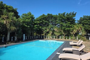 Una piscina al aire libre de temporada, sillones reclinables de piscina