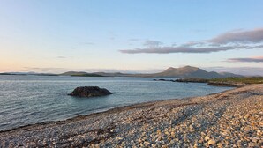 A pebbled beach with calm water, distant mountains, and a clear sky. - Renvyle House Hotel & Resort (Renvyle)