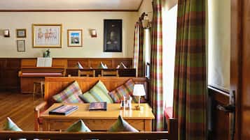 Ein gemütliches Zimmer mit Holzmöbeln, einem Klavier und Kunstwerken an den Wänden.