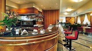 Un moderno vestíbulo de hotel con un mostrador de recepción curvo, zona de estar y un bar.