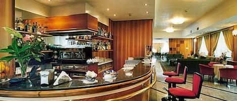 A modern hotel lobby with a curved reception desk, seating area, and a bar.