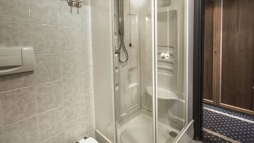 Une salle de bain moderne dotée d’une douche à parois de verre, de toilettes et d’un bidet.
