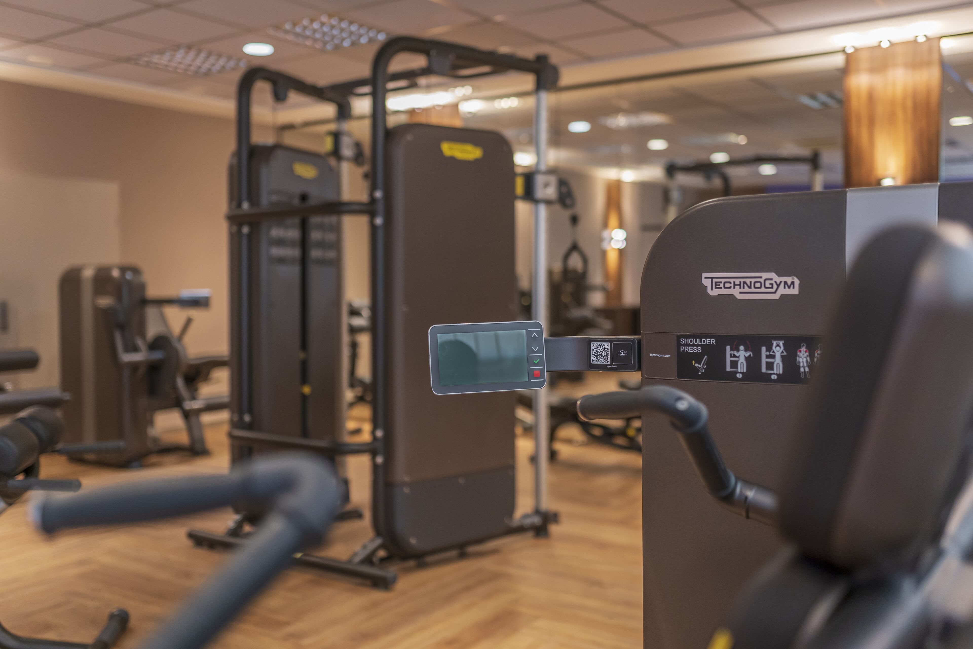 Un gimnasio con equipo de ejercicio diverso, que incluye una máquina de press de banca y una estructura para sentadillas.