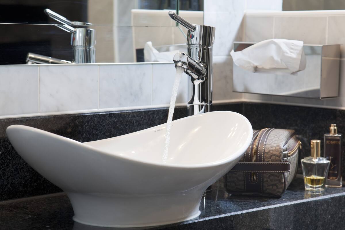 A modern bathroom with a white vessel sink, a chrome faucet, and a marble countertop.
