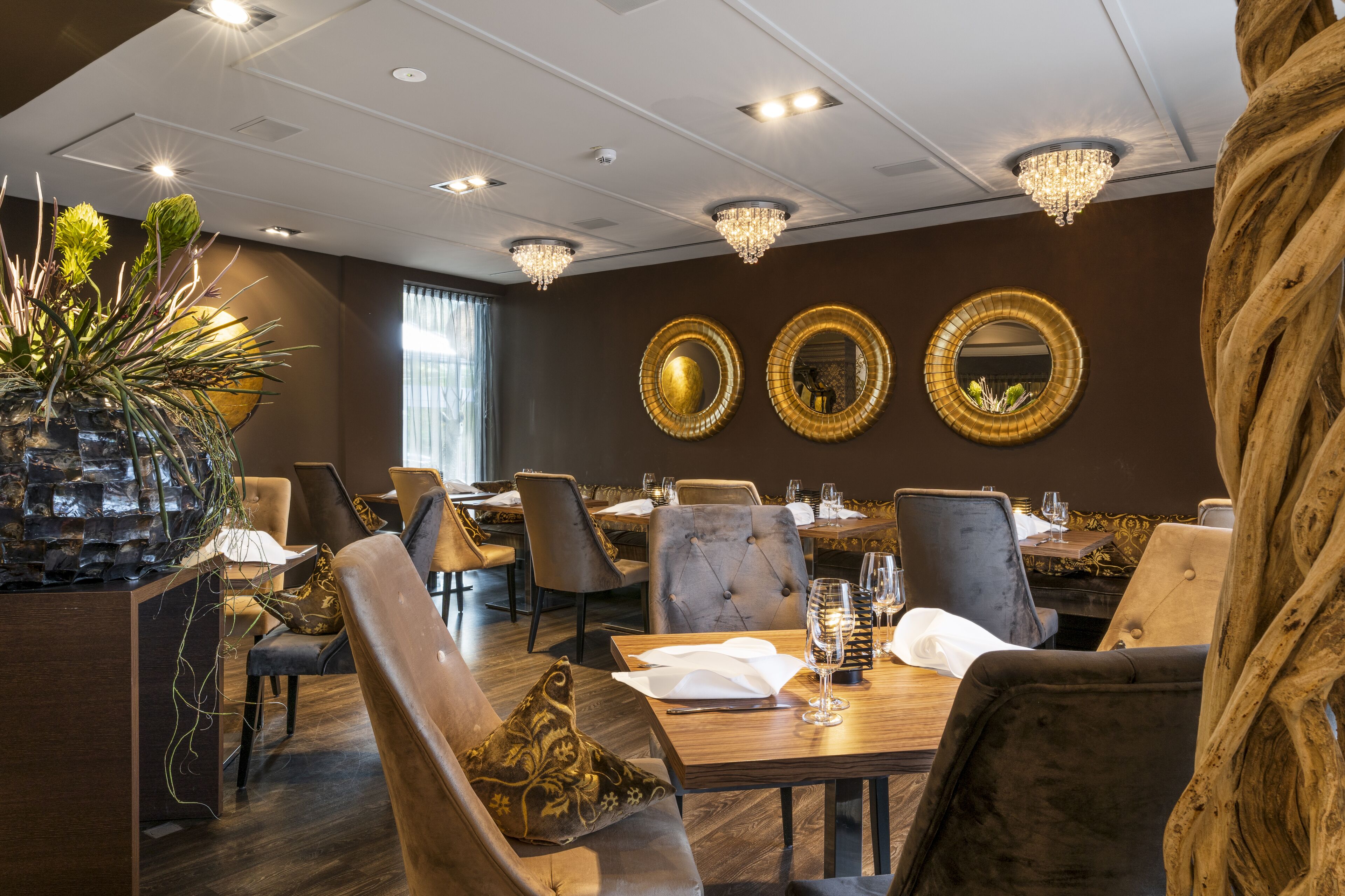 Un restaurante con mesas redondas, sillas de cuero y candelabros.