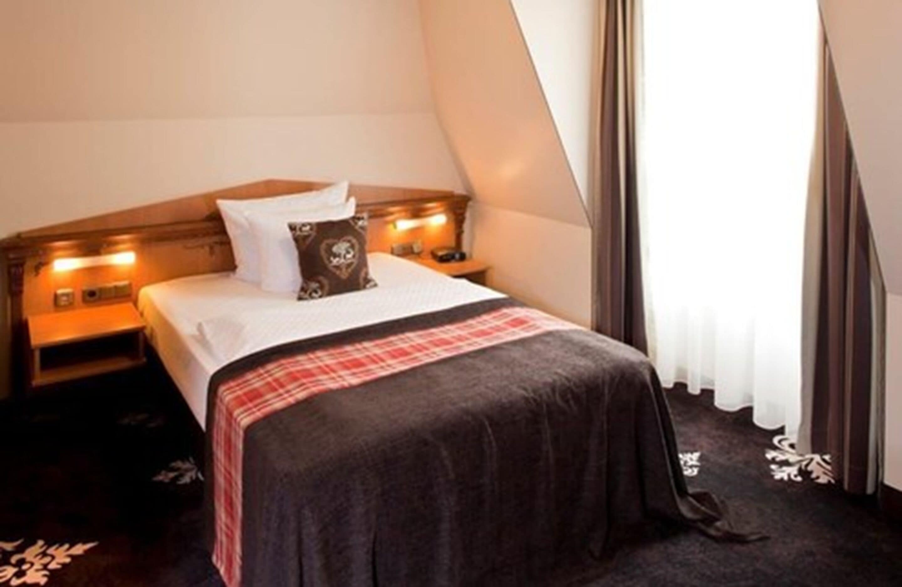 A bedroom with a bed, bedside tables, and a window with curtains.