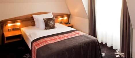 Quarto com cama, mesas de cabeceira e janela com cortinas.