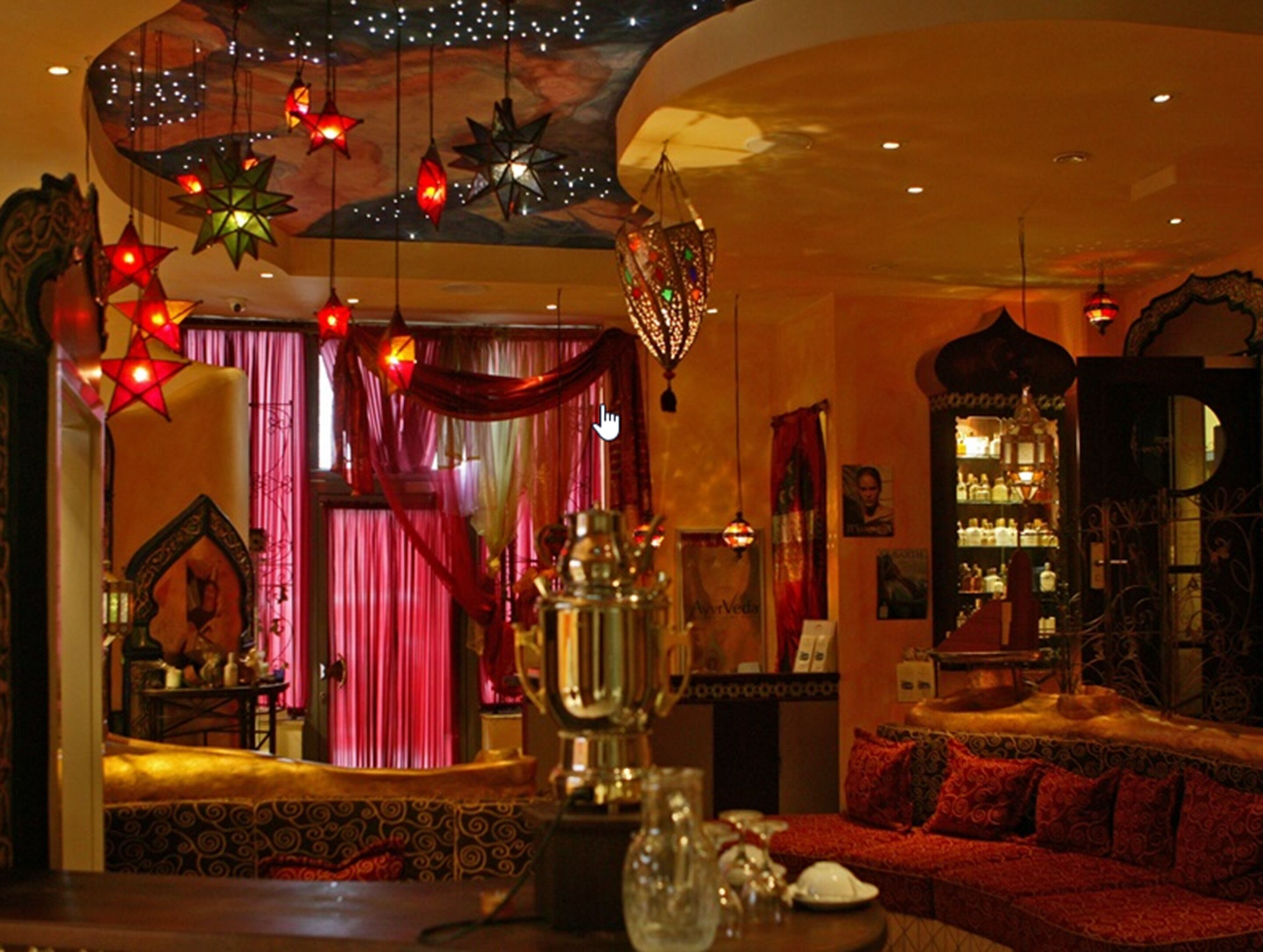 A warmly lit room with a traditional sofa, a decorative lamp, and a bookshelf.