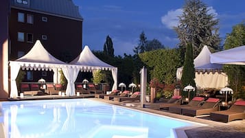 Una piscina techada, una piscina al aire libre, sombrillas