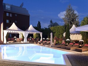 Una piscina techada, una piscina al aire libre, sombrillas