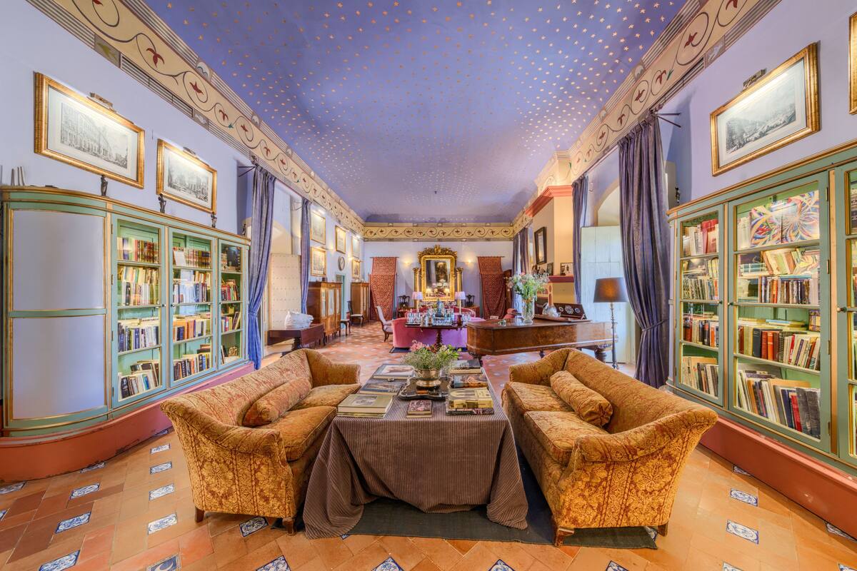 Una biblioteca con dos sofás, una mesa con libros y estanterías a ambos lados.
