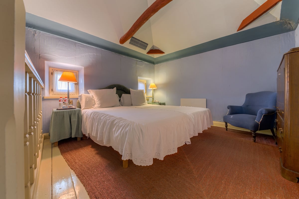 Un dormitorio con una cama grande, una mesita de noche, una silla y un armario.