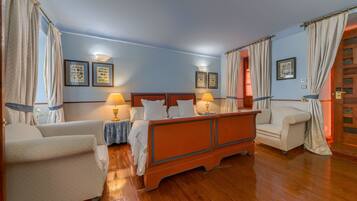 Una habitación de hotel con una cama de madera, dos mesitas de noche con lámparas, un sofá y una silla.