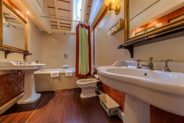 Un baño con un espejo grande, dos lavamanos, una bañera y un inodoro.