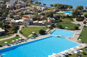 An aerial view of a resort with multiple swimming pools, sun loungers, and a well-maintained lawn. - Kalimera Kriti Hotel & Village Resort (Agios Nikolaos)
