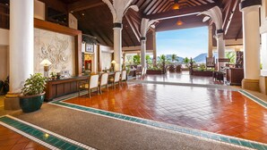 A spacious lobby with a tiled floor, a reception desk, and a view of the mountains.