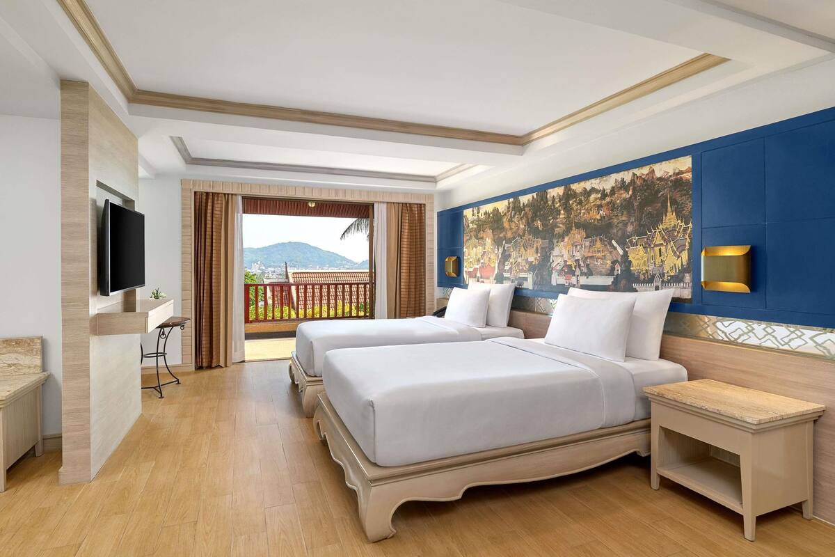 A hotel room with two beds, a TV, a balcony with a view of mountains, and a large painting on the wall.