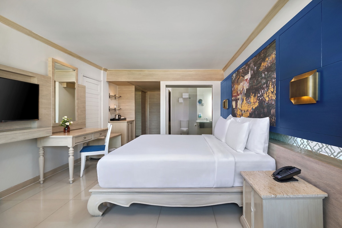 Une chambre d’hôtel avec un lit, un bureau, une chaise, une télévision et un tableau au mur.