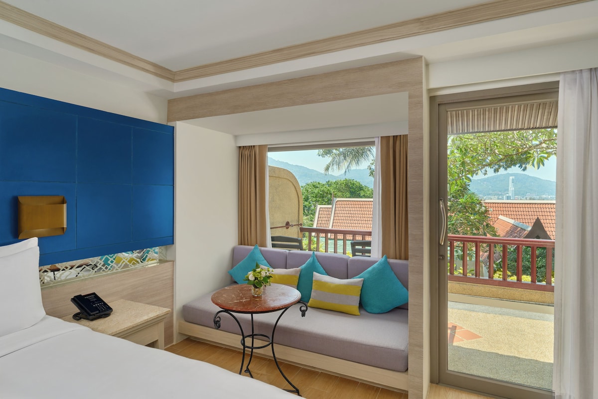 Une chambre d’hôtel avec un lit, un canapé, une petite table, un téléphone et une vue sur l’extérieur.