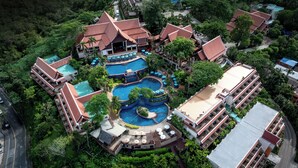 An aerial view of a resort with multiple swimming pools, lush greenery, and a variety of building structures.