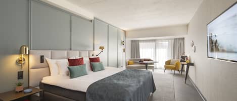 A modern hotel room with a large bed, bedside tables, a desk, and a chair.