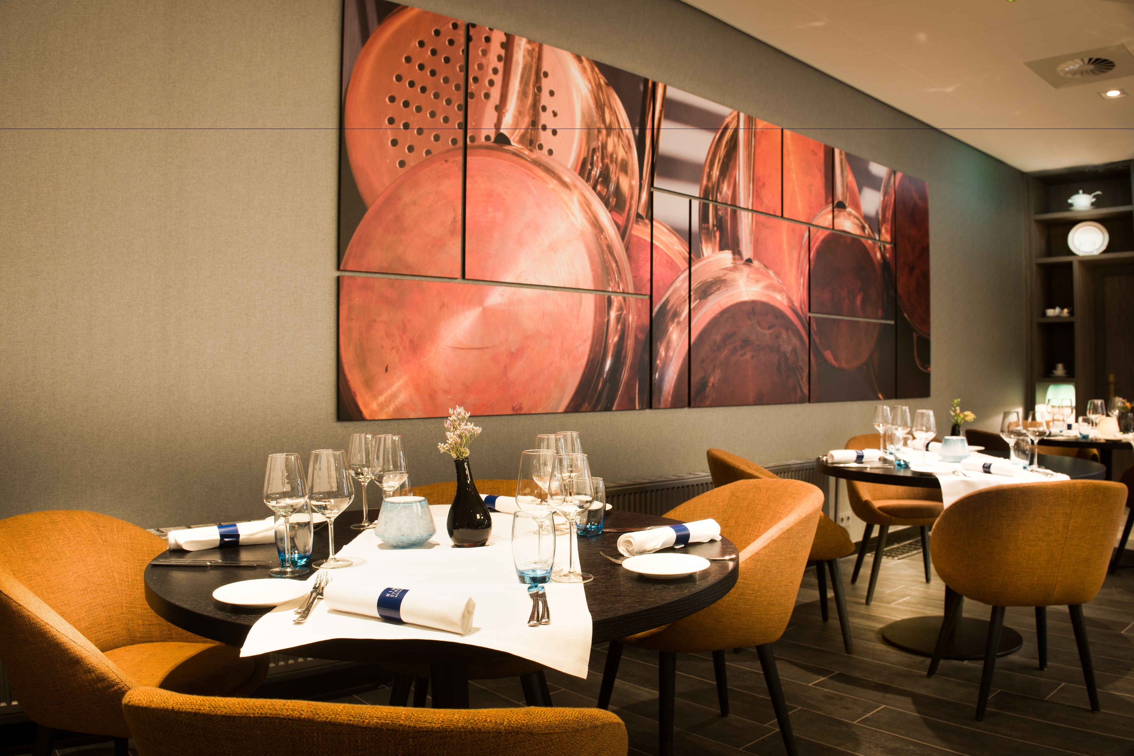 Un restaurante con mesas preparadas para comer, un mural grande en la pared y una decoración interior moderna.