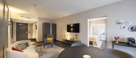 A modern living room with a round table, a sofa, and a TV mounted on the wall.
