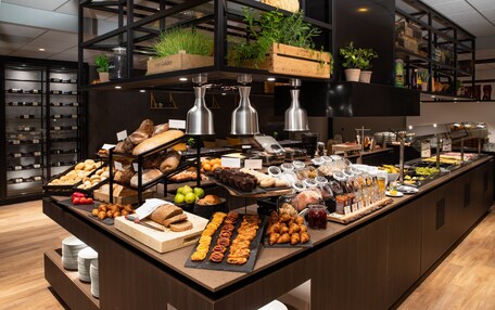 A buffet with various food items and a wine rack in the background.